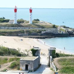 Lighthouse on beach by sea against sky