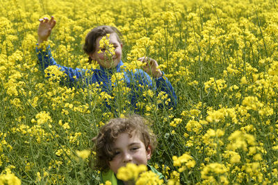 Portrait of woman standing amidst yellow flowering plants on field