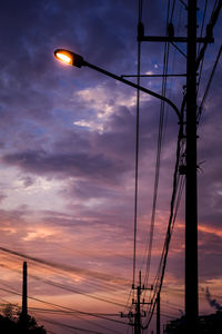 Low angle view of illuminated street lights against sky at sunset