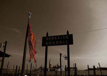 Low angle view of sign flag against sky in city