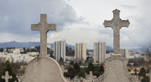 Cross in cemetery against sky