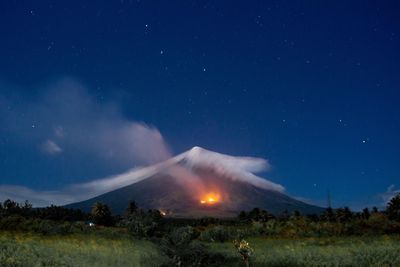 Scenic view of mayon volcano with bush fire at night