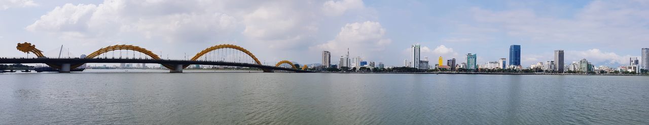 Panoramic view of bridge over river and buildings against sky