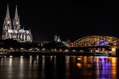 Illuminated buildings by river at night