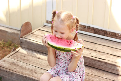 Girl eating watermelon slice sitting on steps