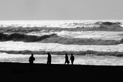 Silhouette people on beach against sky