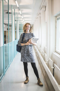 Portrait of smiling young female student in corridor of university