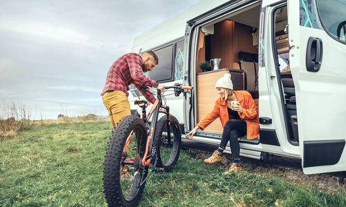 Smiling couple with bicycle by camper van