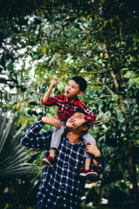 Father and son on tree against plants