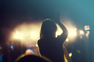 Rear view of woman dancing at music concert