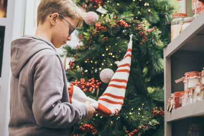 Boy holding decoration while standing in store