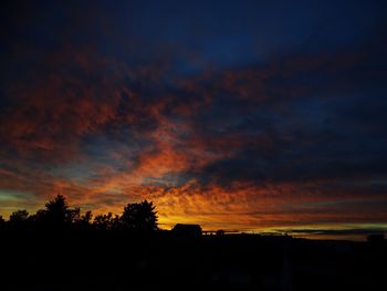 Silhouette trees against cloudy sky during sunset
