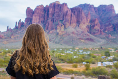 Rear view of woman standing against rocky mountains