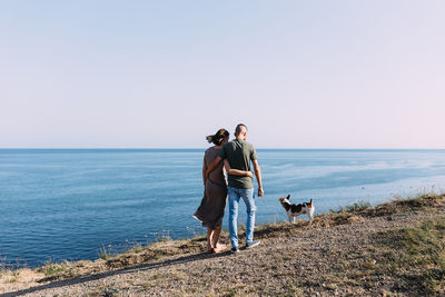 Happy couple with favourite pet. young man and woman have walk near sea.