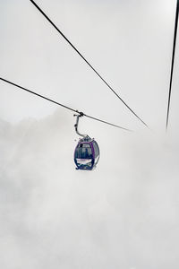 Low angle view of overhead cable car against sky