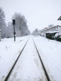 Snow covered railroad tracks against sky during winter