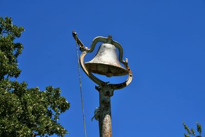Low angle view of old church bell against clear blue sky