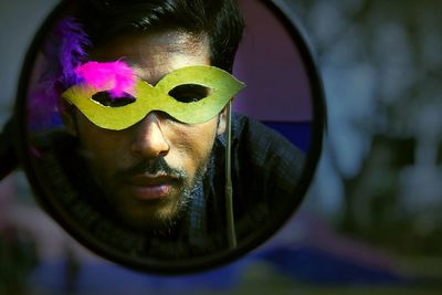 Close-up of man holding eyemask while reflecting on mirror