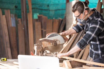 Caucasian man carpenter cutting wood with circular saw creating new furniture person