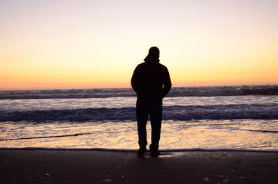 Silhouette man standing on beach during sunset