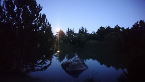 Reflection of trees in lake against sky during winter