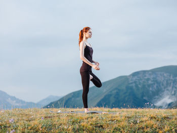 Full length of woman with arms raised against sky