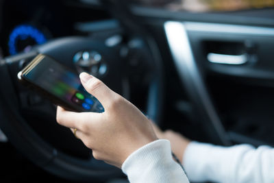 Close-up of hand holding smart phone in car