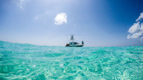 People on yacht sailing in sea against sky