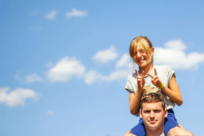 Brother riding sister on back. portrait of happy girl on man shoulders, piggyback. girl fly, horns. 