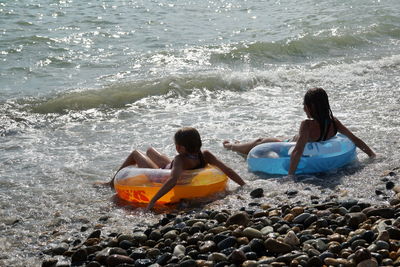 Rear view of people sitting in inflatable ring on beach