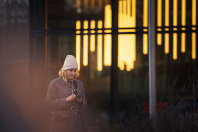 Young woman walking outdoors and using phone