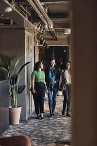 Smiling multiracial businesswomen discussing while walking in office