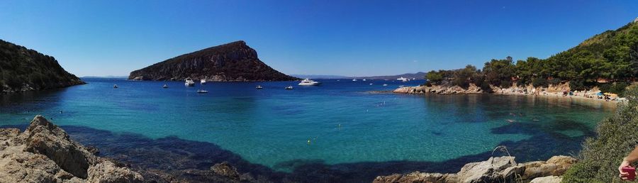 Panoramic view of sea and rocks against clear blue sky