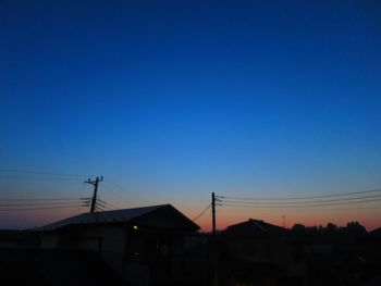 Silhouette houses against clear sky at sunset