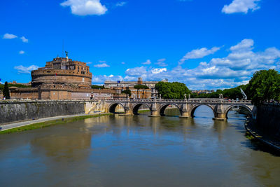 Arch bridge over river against blue sky