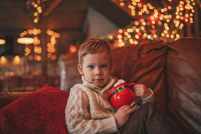 Portrait candid happy kid in knit beige sweater hold xmas mug with marshmallows and candy cane