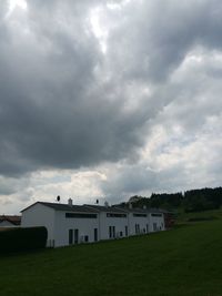 Houses on field against storm clouds