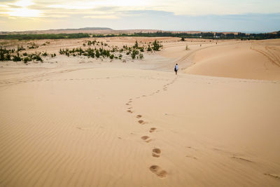 Footprints on sand dune at desert during sunset