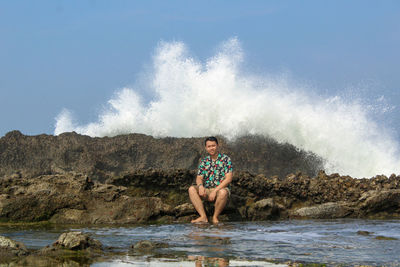 Man surfing on rock in sea