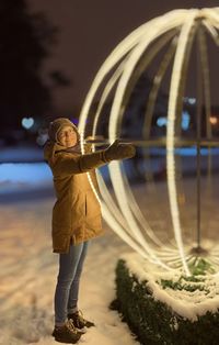 Full length of child standing on illuminated during winter at night