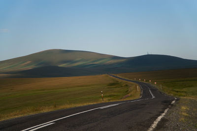 Road by mountains against clear sky