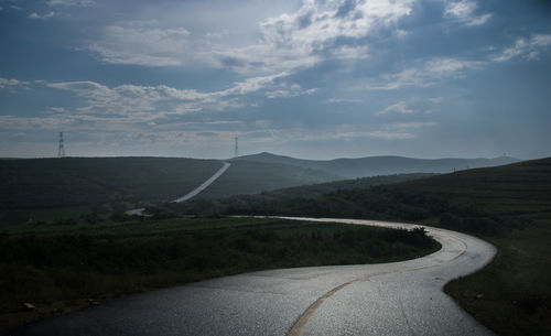Scenic view of road by mountains against sky