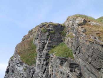 Low angle view of rocks on cliff against sky