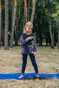 Environmental education for kids. little girl holding young plant in hands against green 