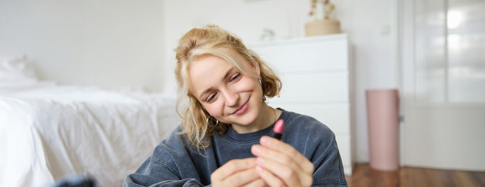 Portrait of smiling young woman using mobile phone while sitting at home