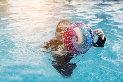 Asian happy kid playing slider in swimming pool