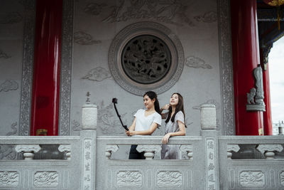 Smiling women embracing while vlogging in corridor