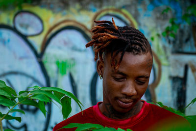 Portrait of a young adult looking down against wall