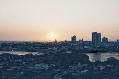 Aerial view of buildings in city against sky during sunset