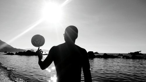 Silhouette man standing by lake against sky